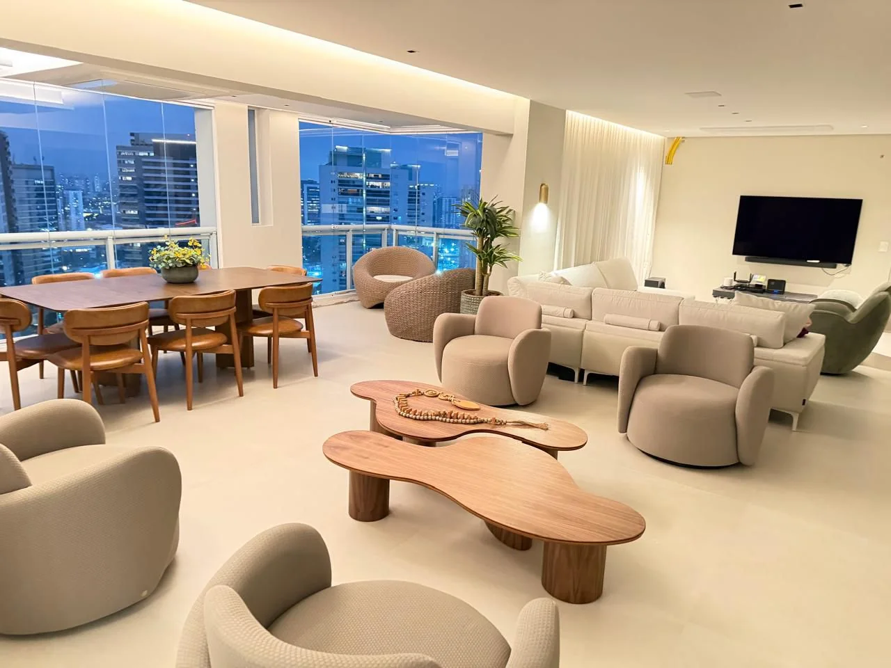Sala de estar integrada à sala de jantar em apartamento reformado, com vista para a cidade ao entardecer