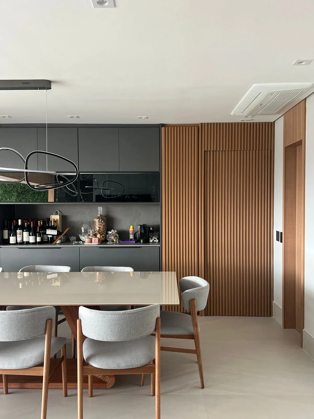 Sala de jantar de alto padrão com adega e painel ripado de madeira